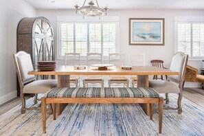 A dining room with a wooden table, white chairs, a bench, and a chandelier. - Enclosed Pool & Sauna Retreat Near Beaches (Fort Walton Beach)