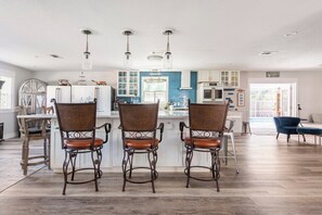 A kitchen with a central island, bar stools, and pendant lighting. - Enclosed Pool & Sauna Retreat Near Beaches (Fort Walton Beach)