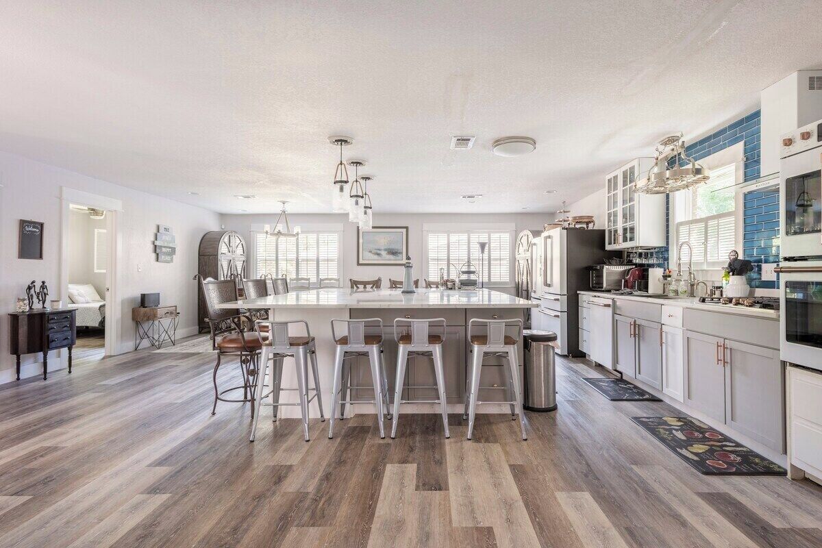 A spacious kitchen with a central island, bar stools, and a large window providing natural light.