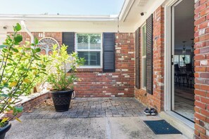 A brick exterior with a door leading to a covered patio area. - Enclosed Pool & Sauna Retreat Near Beaches (Fort Walton Beach)