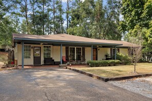 A single-story building with a covered porch, a front door, and a small front yard.