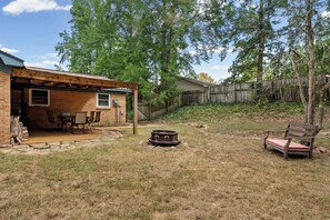 A backyard with a patio, a fire pit, and a wooden fence.