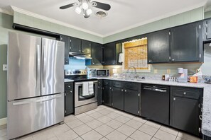 A modern kitchen with stainless steel appliances, black cabinets, and a tiled floor. - Local on Lamar. 5 min to square or campus. Ranch-style home on S Lamar. (Oxford)