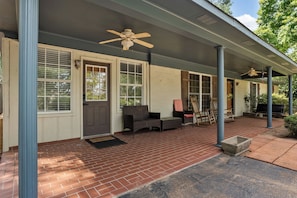 A covered porch with a brick floor, a bench, and a door with a window. - Local on Lamar. 5 min to square or campus. Ranch-style home on S Lamar. (Oxford)