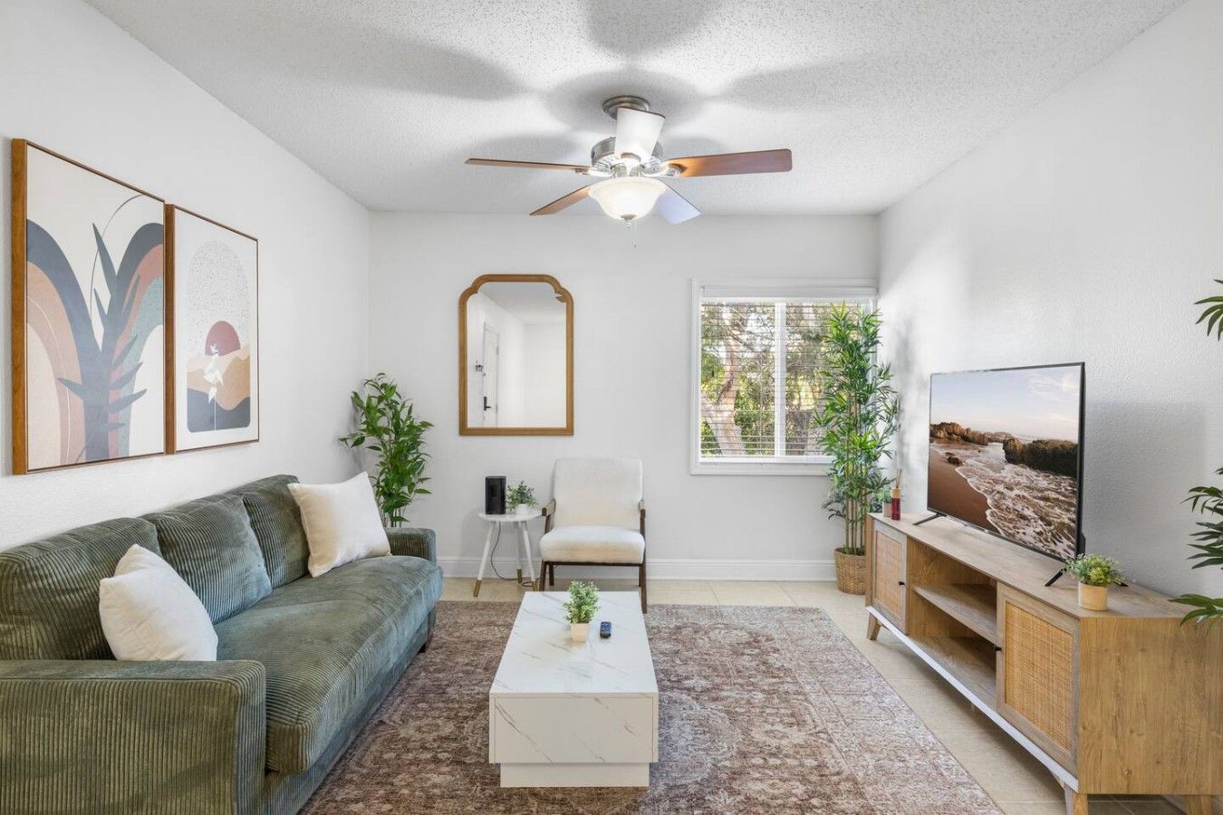 A living room with a sofa, armchair, coffee table, and a television on a wooden stand.