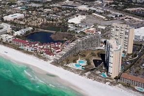 An aerial view of a coastal resort with a large hotel, multiple swimming pools, and a beach. - Miramar Beach Getaway Steps away from the beach (Miramar Beach)