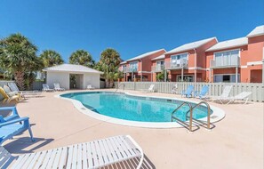 Un espace piscine avec des chaises longues et un petit bâtiment, probablement un bar au bord de la piscine ou un vestiaire.