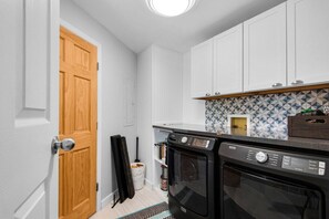 A compact kitchen with white cabinetry, a built-in oven, and a patterned backsplash. - Gorgeous Waterfront Home! (Fort Walton Beach)