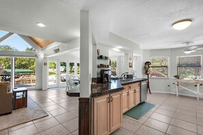 A spacious kitchen with a large island, wooden cabinets, and a view to an outdoor patio area. - Gorgeous Waterfront Home! (Fort Walton Beach)