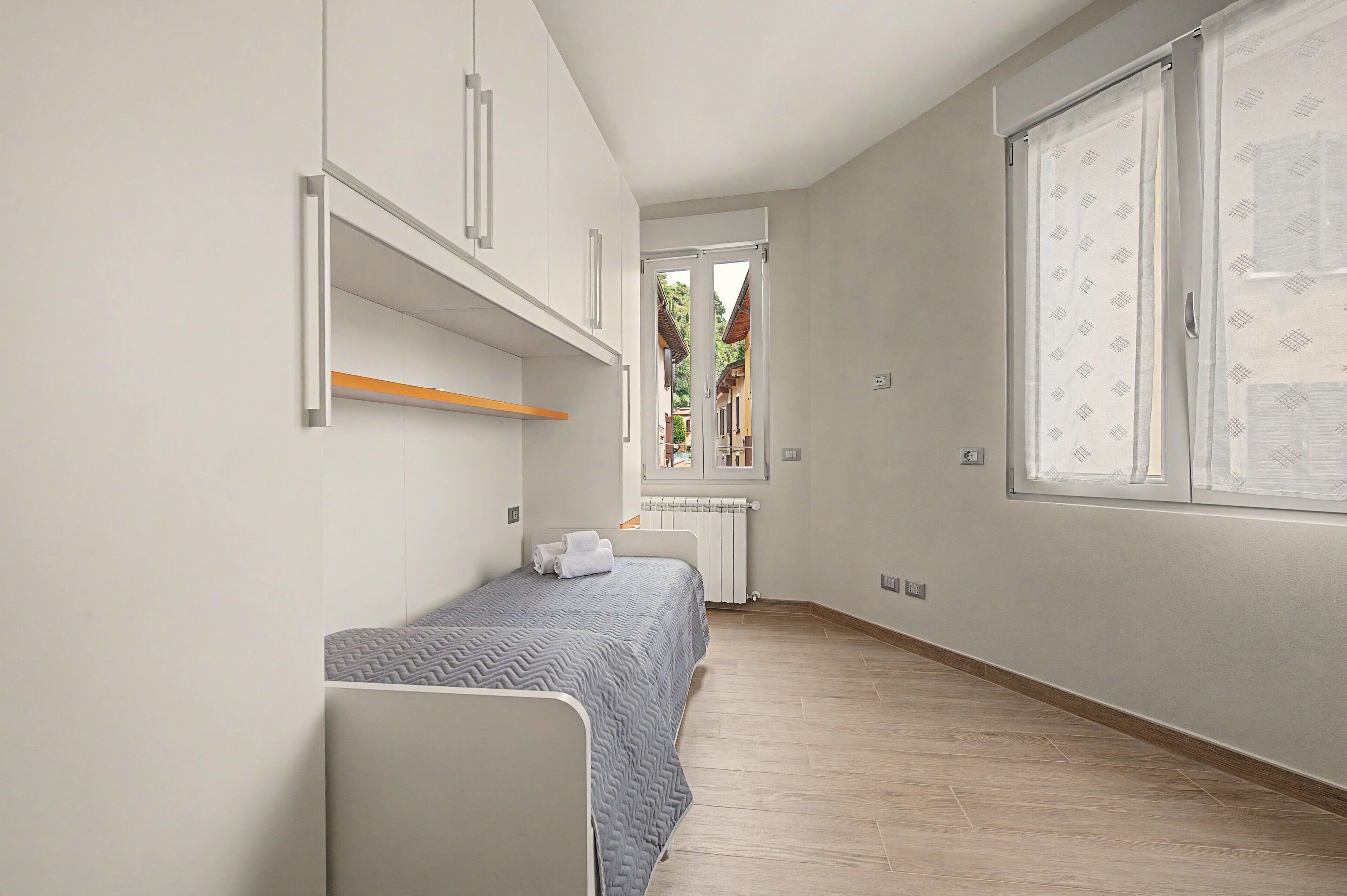 Una camera da letto con un letto singolo, una finestra vista e un termosifone.