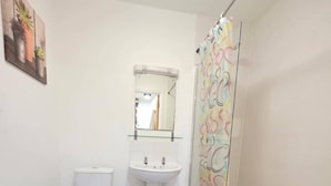 A bathroom with a toilet, sink, and shower. There are blue mats on the floor. - Cozy City 1Br W/balcony at the Heart of Stratford (London)
