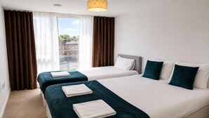 A hotel room with two beds, a window with curtains, and a view of buildings outside. - Cozy City 1Br W/balcony at the Heart of Stratford (London)