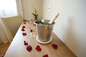 Ein Tisch mit einem Champagnerkühler, Gläsern und Rosenblütenblättern.