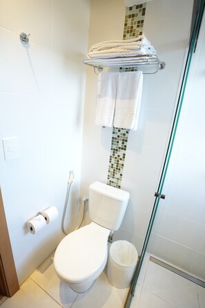 Ein Badezimmer mit Toilette, Dusche, Handtuchhalter und Toilettenpapierhalter.