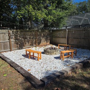 Ein Garten mit Feuerstelle, Holzbanken und einem Holzzaun.