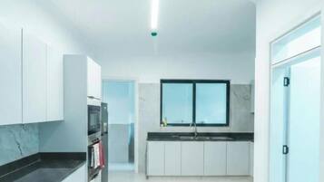 A modern kitchen with white cabinets, a black countertop, a built-in oven, and a window above the sink.