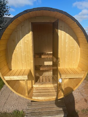 A wooden sauna with a circular shape, a bench, and a bench seat. - Song Sparrow Cottage - Barrel Sauna / Water Views / Short walk to beach (North Rustico)