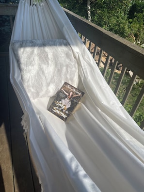 Eine Hängematte mit einem Buch mit dem Titel 'Song of the Sparrow' auf einem Holzdeck.