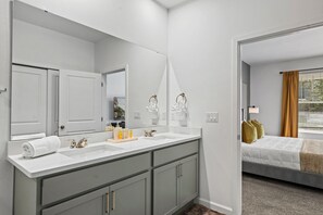 A modern bathroom with dual sinks, a large mirror, and a walk-in closet. - Brand New   6BR Villa Pool   Spa  PS5 Loft 2380 (Kissimmee)