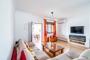 Ein Wohnzimmer mit einer Sofagarnitur, einem Couchtisch, einem Fernseher und einem Kamin.