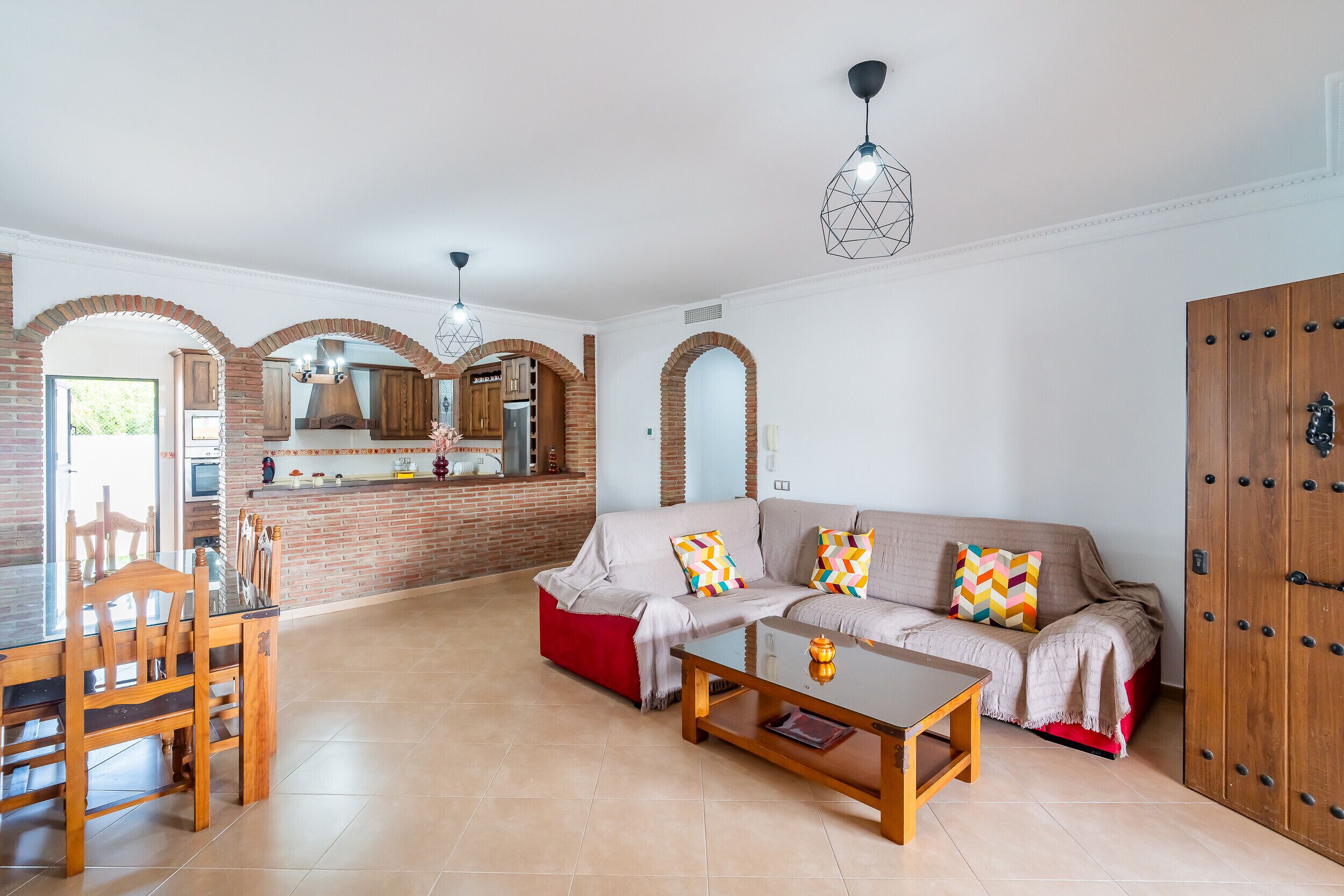 A living room with a sofa, coffee table, and a dining area with chairs and a table.