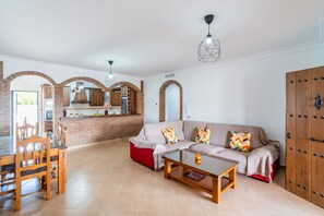 Een woonkamer met een bank, salontafel en een eethoek met stoelen en een tafel.