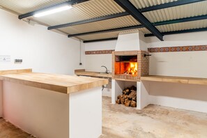 A kitchen with a built-in wood-burning stove, a countertop, and a tiled backsplash. - Cubo's Casa San Francisco & Private Pool / air conditioning / BBQ / free wifi (Málaga)