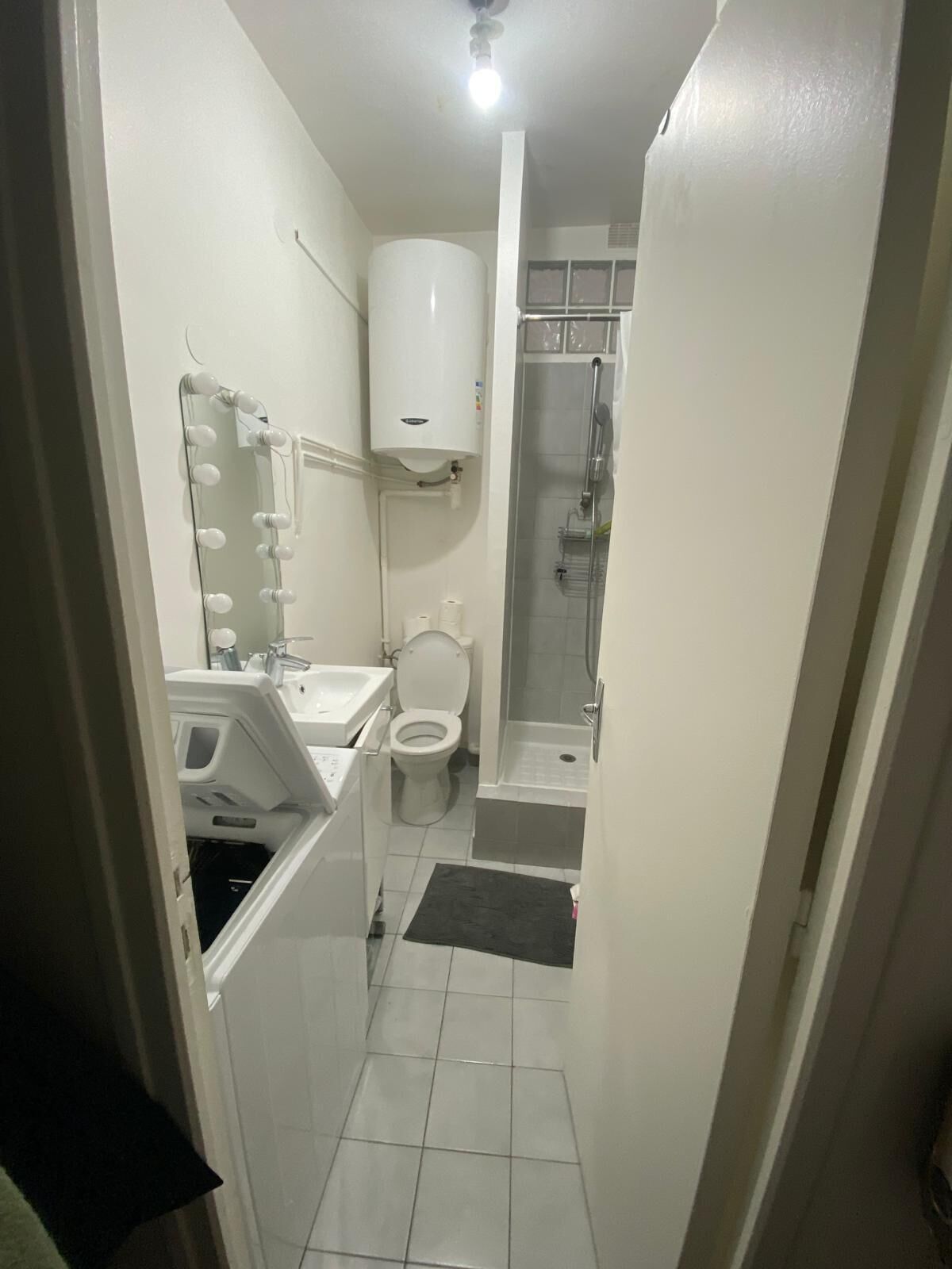 A compact bathroom with a toilet, sink, and shower.