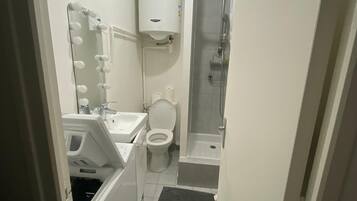 Een kleine badkamer met toilet, wastafel en douche.