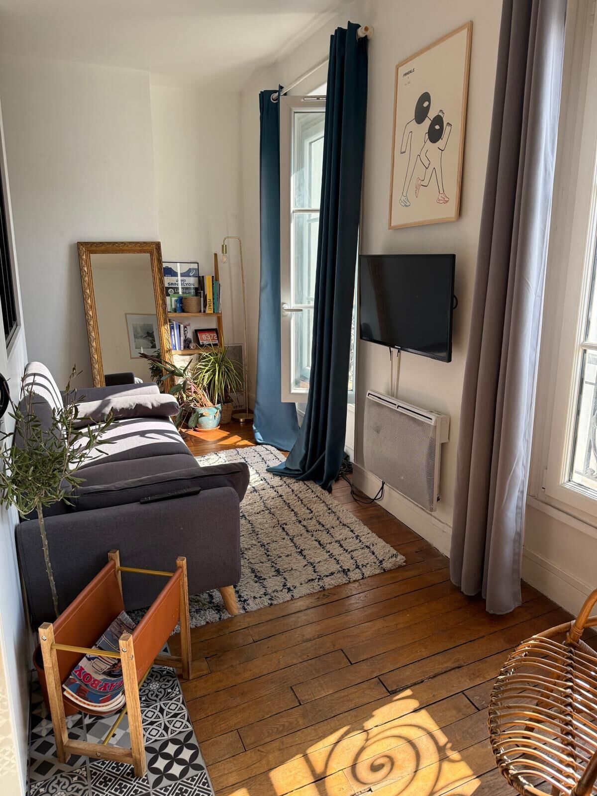 A cozy living room with a sofa, a chair, a TV, and a large mirror.