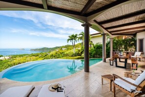 Ein Poolbereich mit Meerblick, eine überdachte Terrasse mit Sitzgelegenheiten und ein Essbereich.