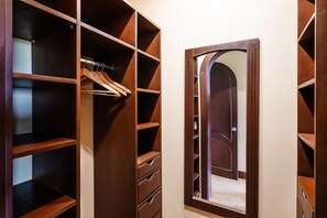 Ein begehbarer Kleiderschrank mit mehreren Regalen und Schubladen, einem Spiegel und einer Tür.