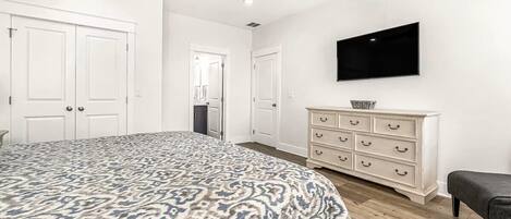 A bedroom with a bed, a dresser, a television, and a ceiling fan.
