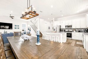 A spacious kitchen with white cabinetry, a wooden dining table, and a central island with stools. - Clear Sky: Private Pool & Spa | FREE Golf Cart | 2 Family Rooms | Walk to Beach (Destin)