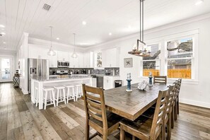 Une cuisine moderne avec des meubles blancs, une table à manger en bois et des tabourets de bar.
