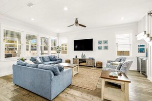 A spacious living room with a large sofa, a coffee table, and a flat-screen TV mounted on the wall. - Clear Sky: Private Pool & Spa | FREE Golf Cart | 2 Family Rooms | Walk to Beach (Destin)