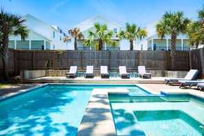 A swimming pool with lounge chairs, a wooden fence, and a white building with multiple windows in the background. - Clear Sky: Private Pool & Spa | FREE Golf Cart | 2 Family Rooms | Walk to Beach (Destin)