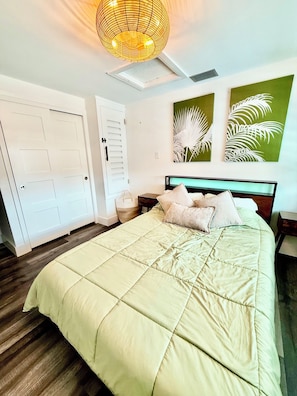 Un dormitorio con una cama, una mesita de noche, una lámpara de pared y dos puertas.