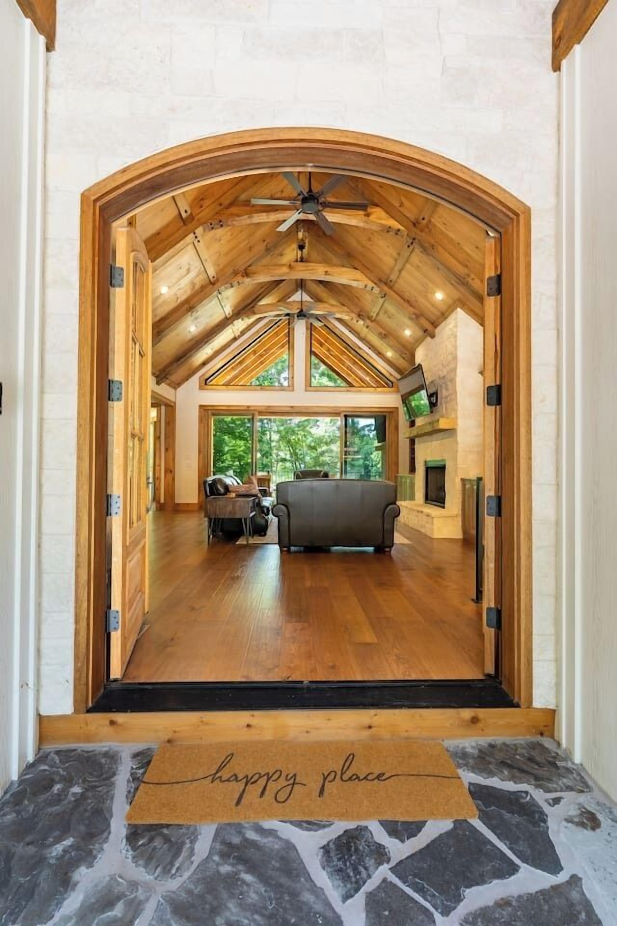 Una entrada de madera arqueada que da a una sala de estar con chimenea, un sofá y un televisor.