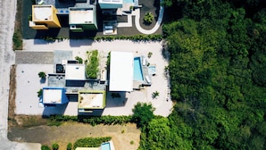 Vue aérienne d’une propriété comprenant plusieurs bâtiments, une piscine et de nombreux espaces verts.