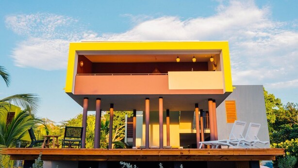 Un bâtiment moderne doté d’un toit plat, d’un balcon avec des chaises et d’une terrasse en bois.