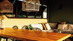 Un intérieur moderne avec une table à manger en bois, des chaises en osier et un canapé agrémenté de coussins à motifs.