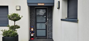 A modern building entrance with a welcome sign, a glass door, and a nutcracker figure outside. - Holiday Home 'Welcome' with Terraces, Private Garden and Wi-Fi (Le Relecq-Kerhuon)