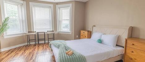 A bedroom with a bed, bedside tables, a desk, and a ceiling fan.