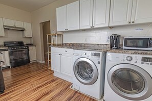 A kitchen with a stove, oven, microwave, and washing machines. - Mount Washington 4BR Home, Sleeps 10, 2 Kitchens (Pittsburgh)