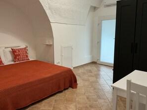 A bedroom with a bed, a white table, and a black wardrobe. - Vrbo Property (Polignano a Mare)