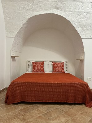 A bed with a red cover, white pillows, and a white headboard under an arched white ceiling. - Vrbo Property (Polignano a Mare)