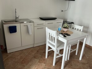 A compact kitchen with a sink, countertop, and a dining table with chairs. - Vrbo Property (Polignano a Mare)