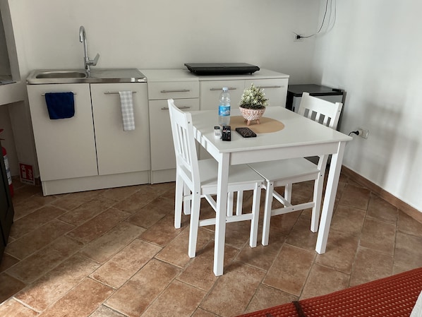 A small kitchenette with a sink, a countertop, and a table with chairs. - Vrbo Property (Polignano a Mare)