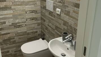 A bathroom with a toilet, sink, and a mirror.